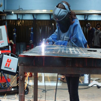 Student using plasma to cut metal